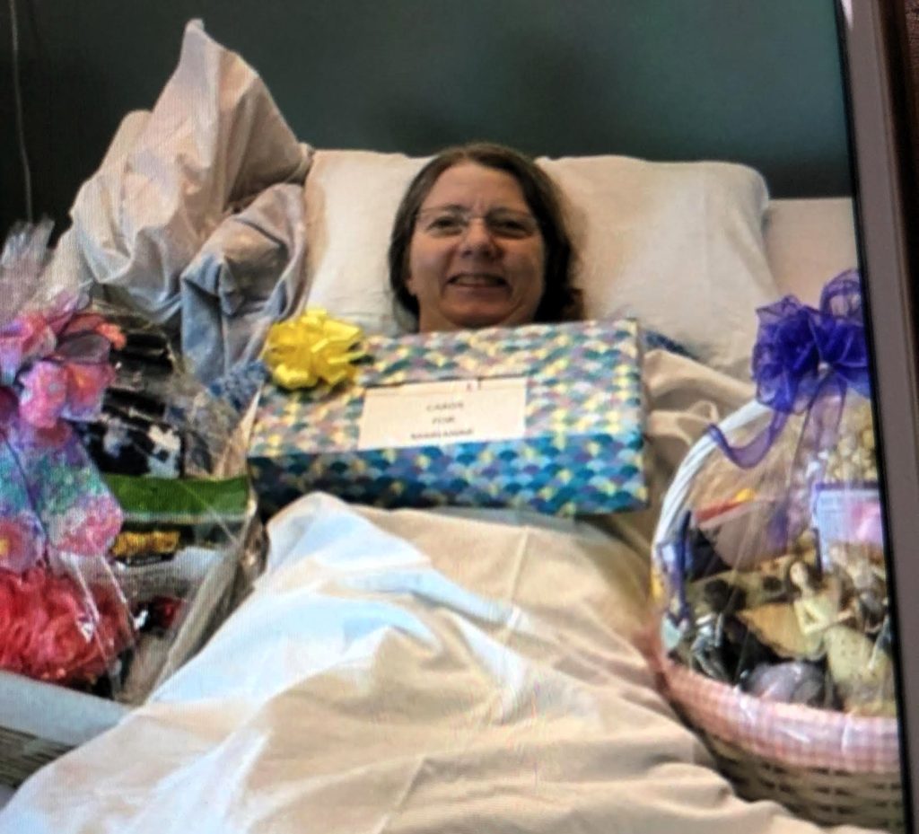 Marianne smiling in hospital bed with presents